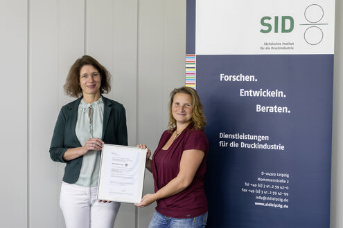 Beatrix Genest, Prokuristin des Sächsischen Instituts für die Druckindustrie (links) und Carolin Sommerer, Leiterin des Prüflabors präsentieren stolz die Akkreditierungsurkunde